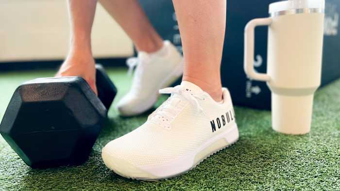 Close up image of athlete wearing Nobull Trainer+ Shoes and grabbing a dumbbell.
